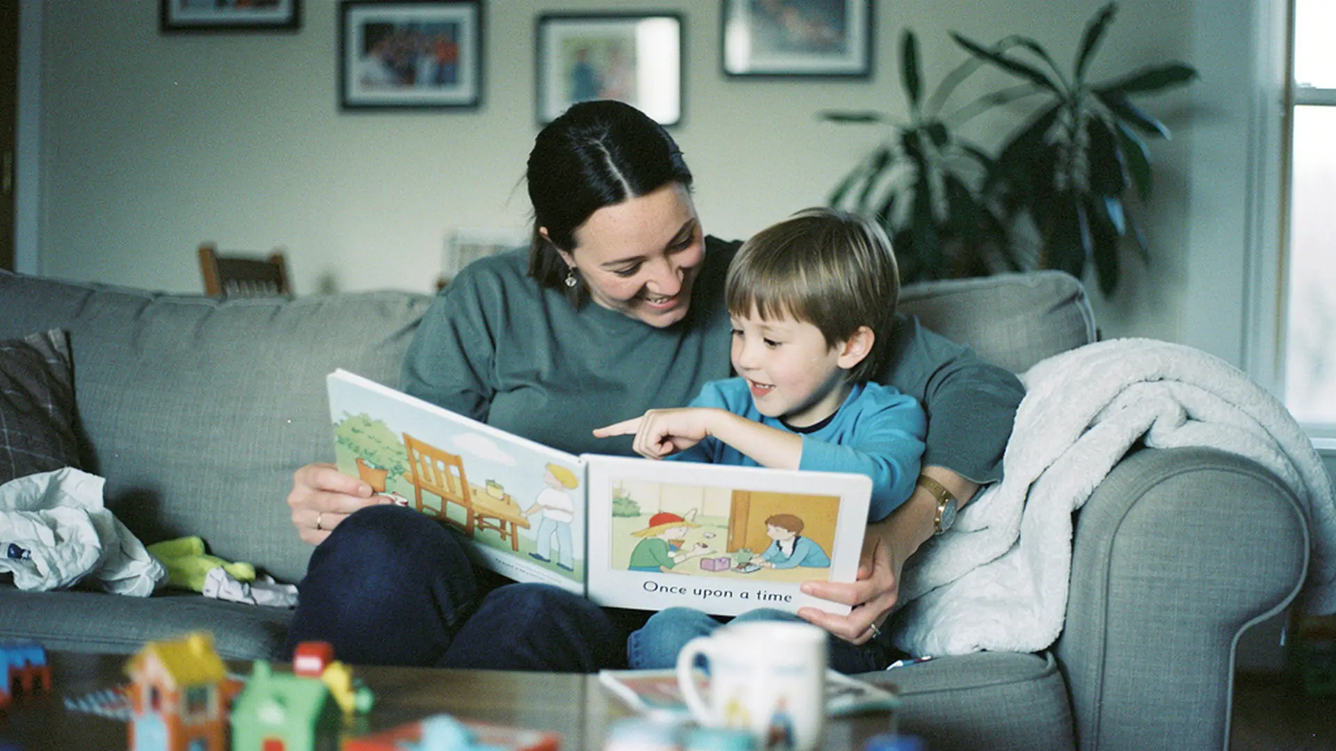 Parent et enfant assis sur un canapé en train de lire ensemble un livre