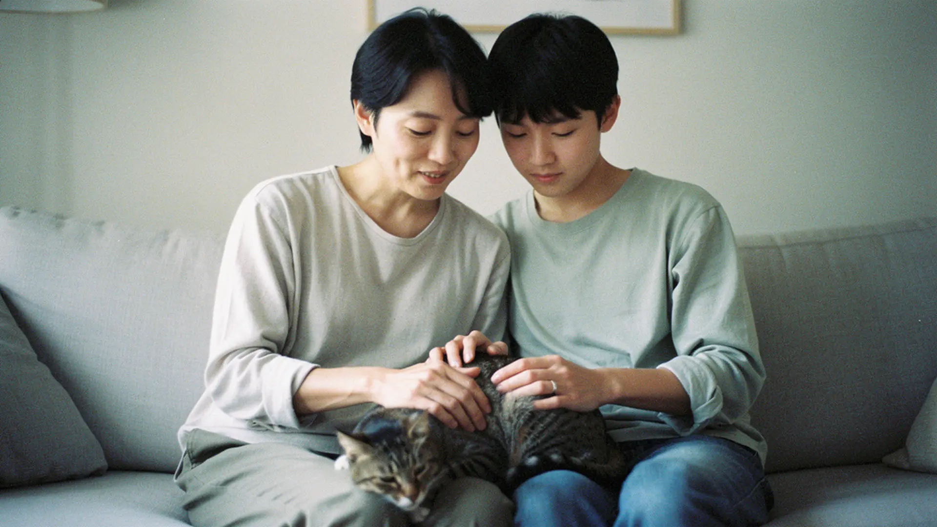 Parent assis avec son enfant caressant un chat âgé sur un canapé