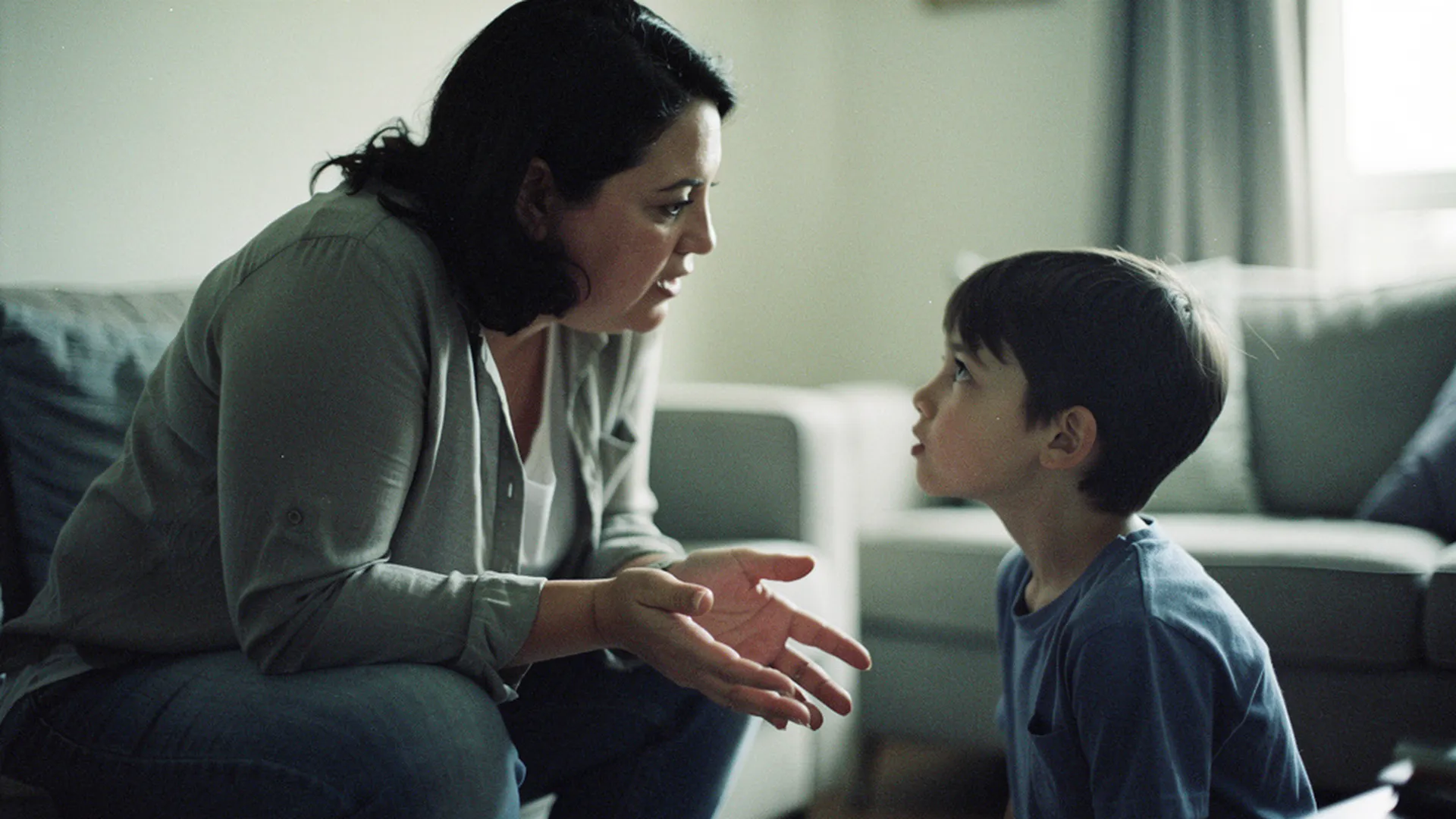 Parent assis au niveau des yeux de son enfant dans un salon calme, en pleine conversation