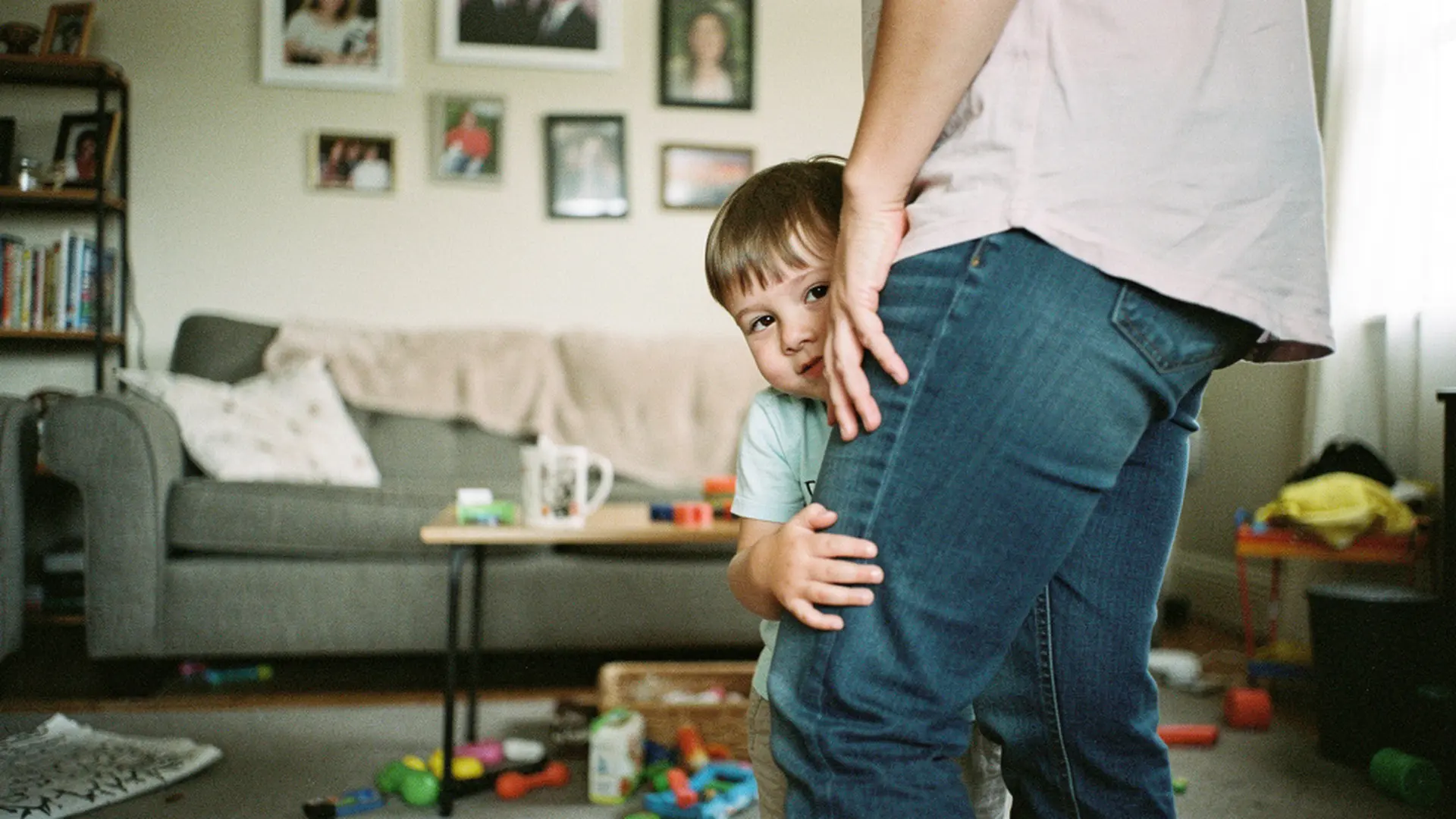 Enfant de 6 ans se cachant timidement derrière la jambe de sa mère lors d'une réunion de famille