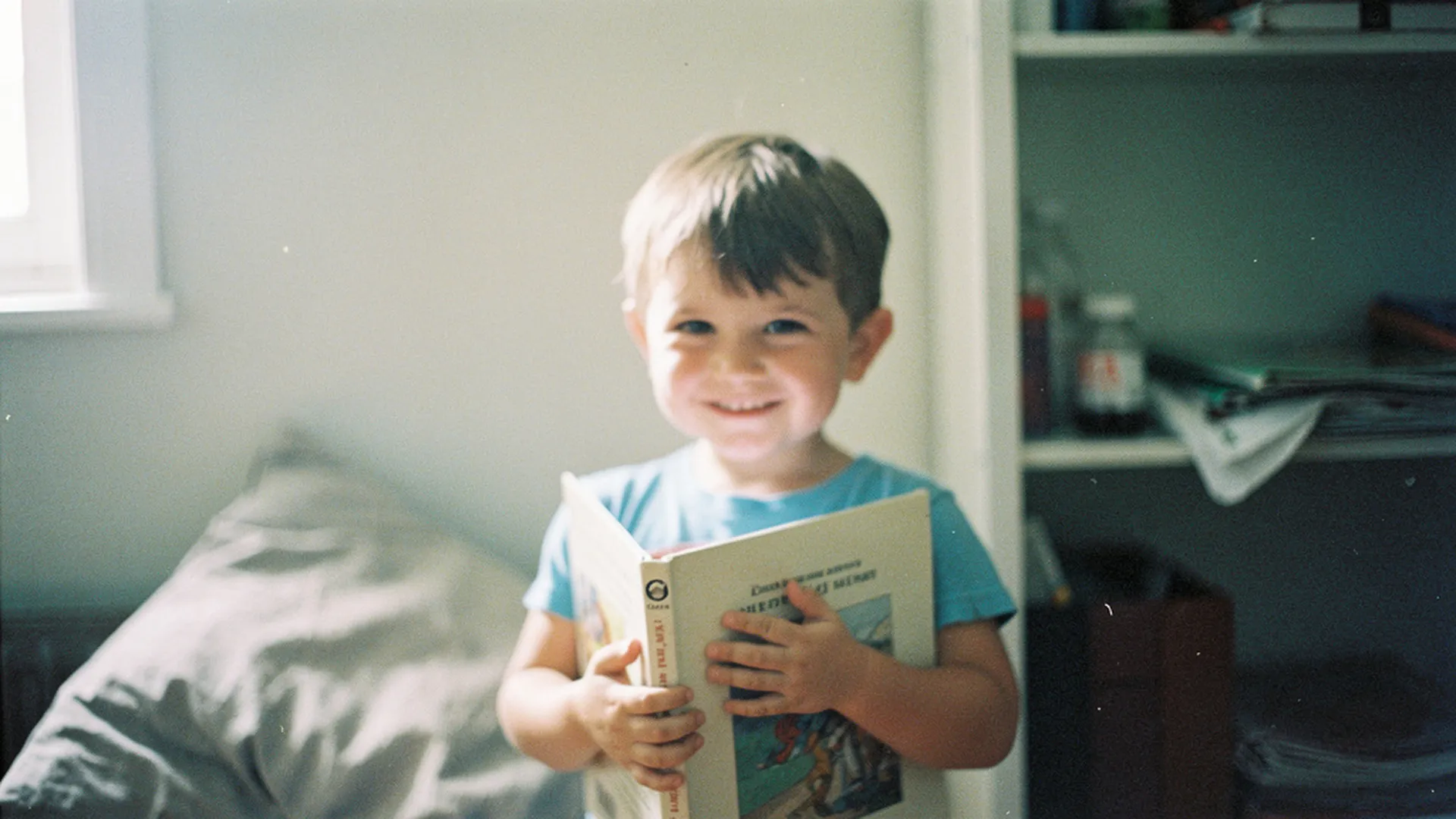 Enfant de 5 ans souriant, tenant un livre ouvert contre lui